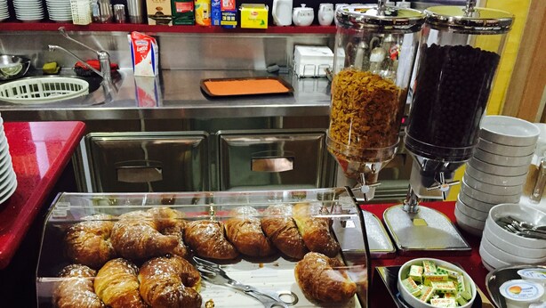 A buffet counter with a variety of food items, including pastries and a beverage dispenser. - Hotel Cristal Eboli (Eboli)