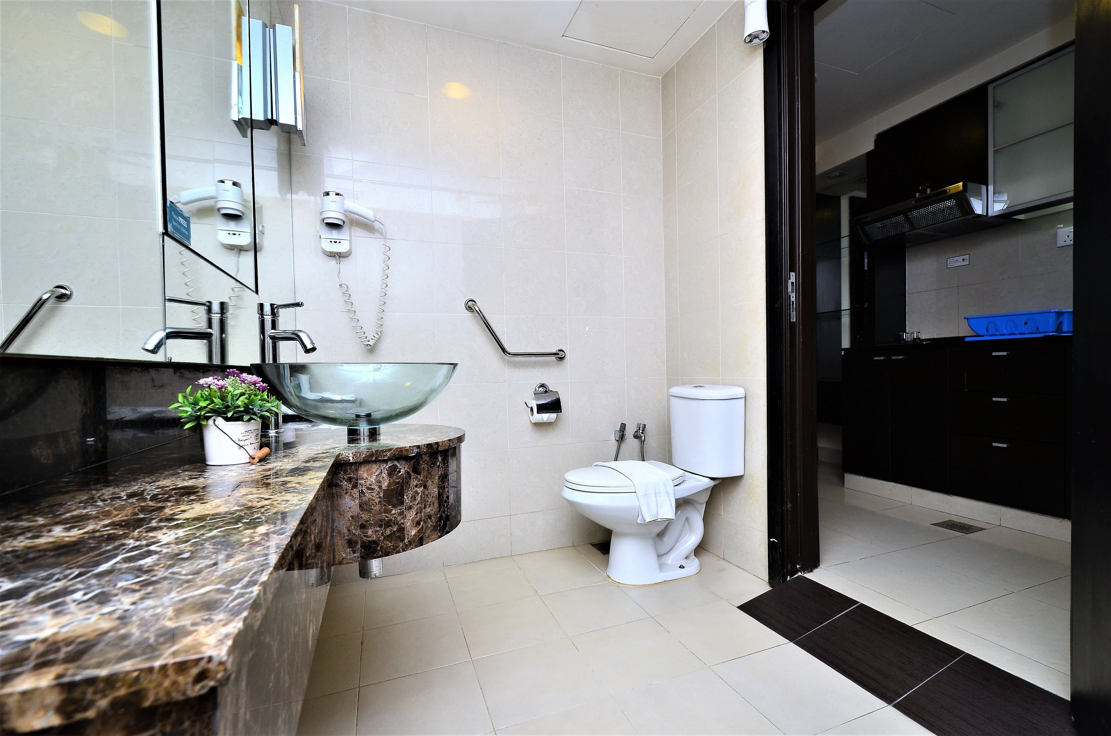 A modern bathroom with a marble sink, a glass bowl, a white toilet, and a black cabinet.