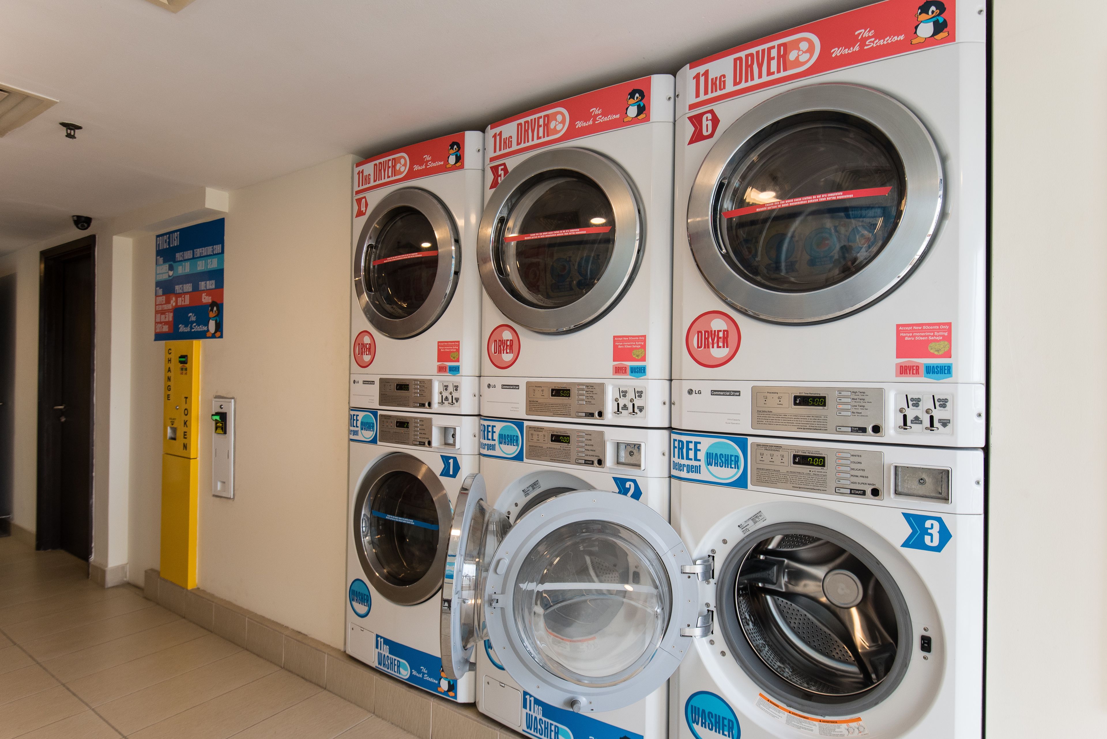 A row of front-loading washing machines with digital displays, arranged in a commercial setting.