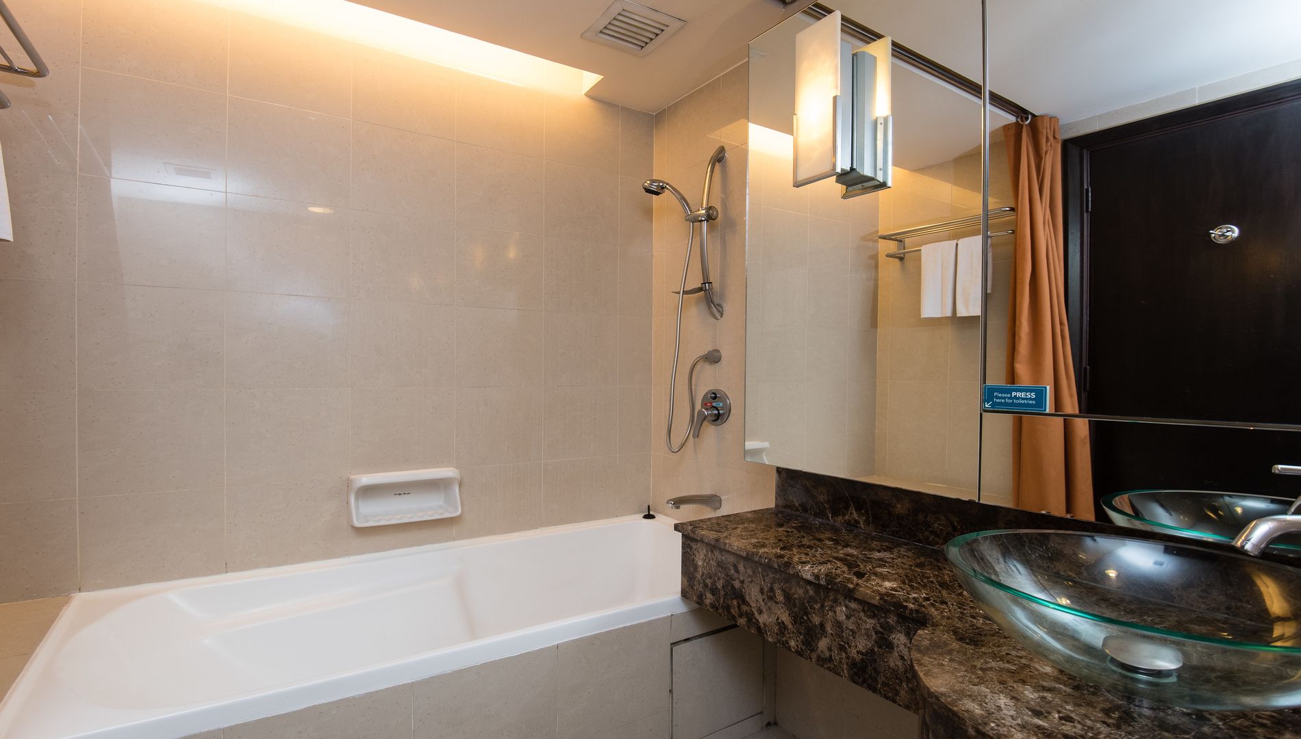 Un baño moderno con bañera, lavamanos de vidrio y ducha con cabezal de ducha manual.