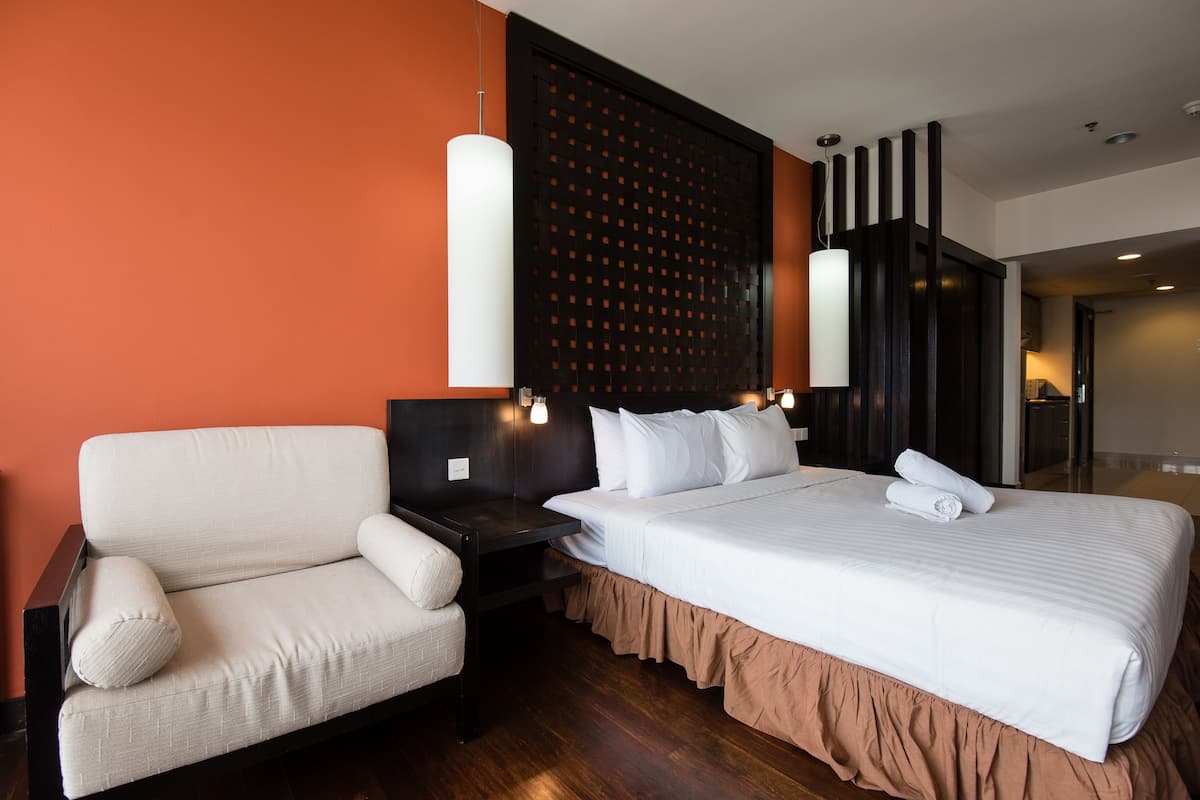 A hotel room with a sofa, a large bed, and a wooden headboard.