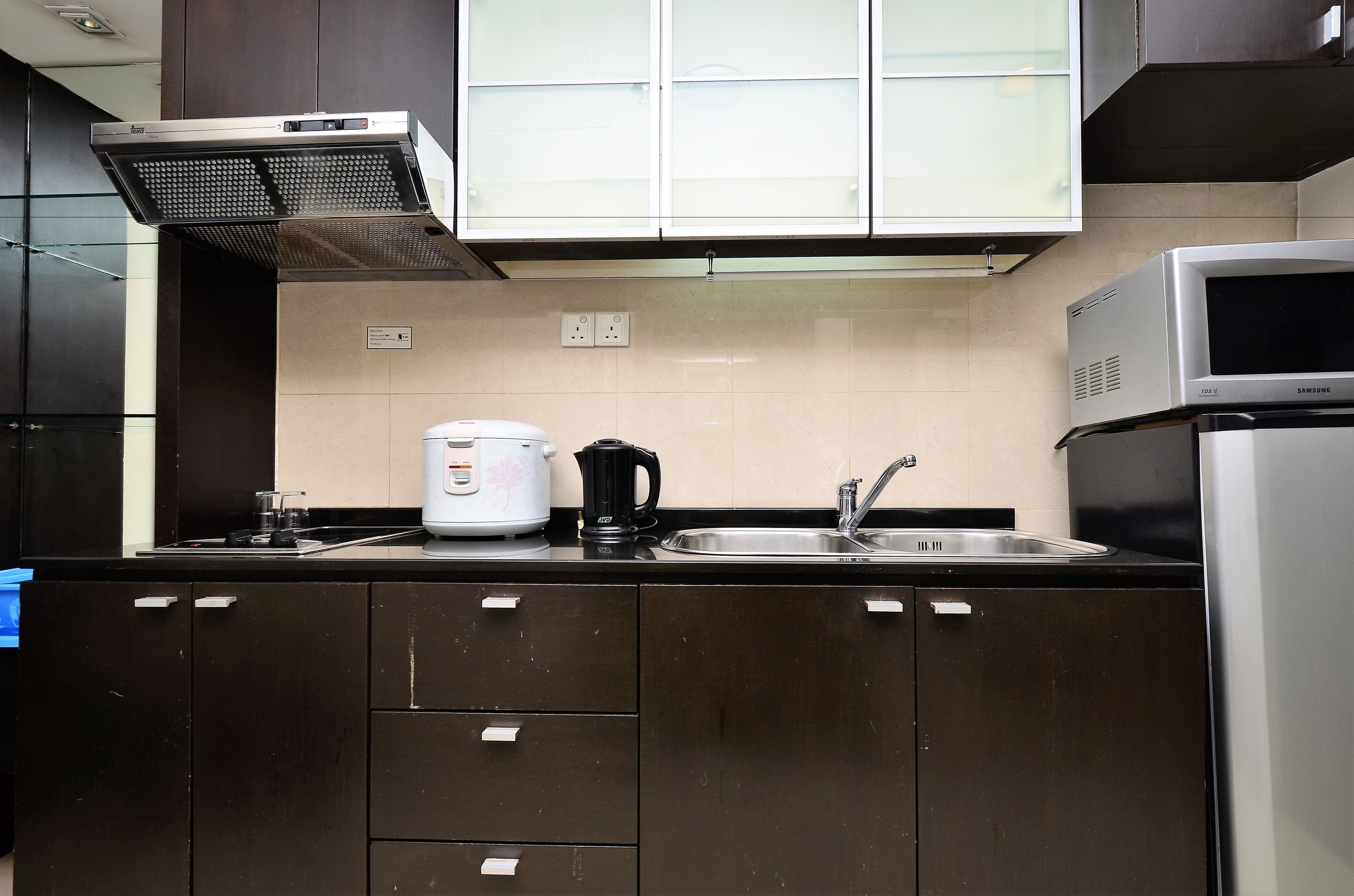 Une cuisine moderne avec des meubles de couleur sombre, un évier en acier inoxydable, une machine à café et un four à micro-ondes.