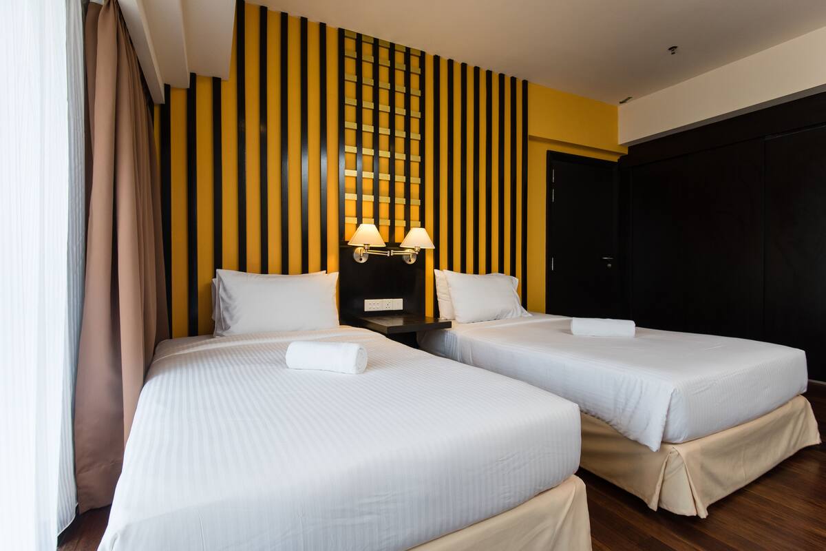 A hotel room with two beds, a wall with vertical stripes, and a door.