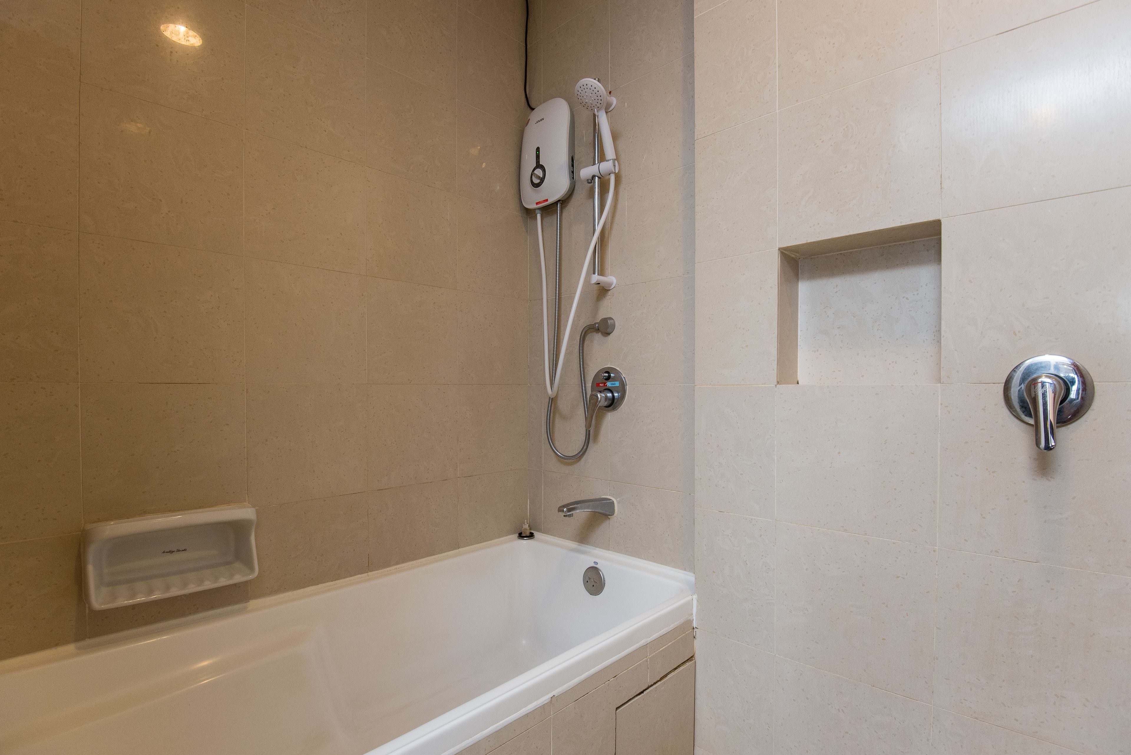 A modern bathroom with a bathtub, a handheld showerhead, and a wall-mounted faucet.