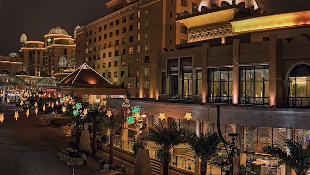 Um hotel de vários andares com uma cúpula imponente e uma ampla área de entrada com palmeiras e luzes em formato de estrela.