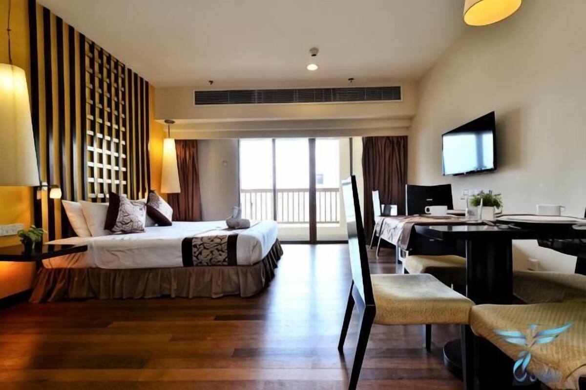 A hotel room with a bed, a desk, a chair, a TV, and a balcony.