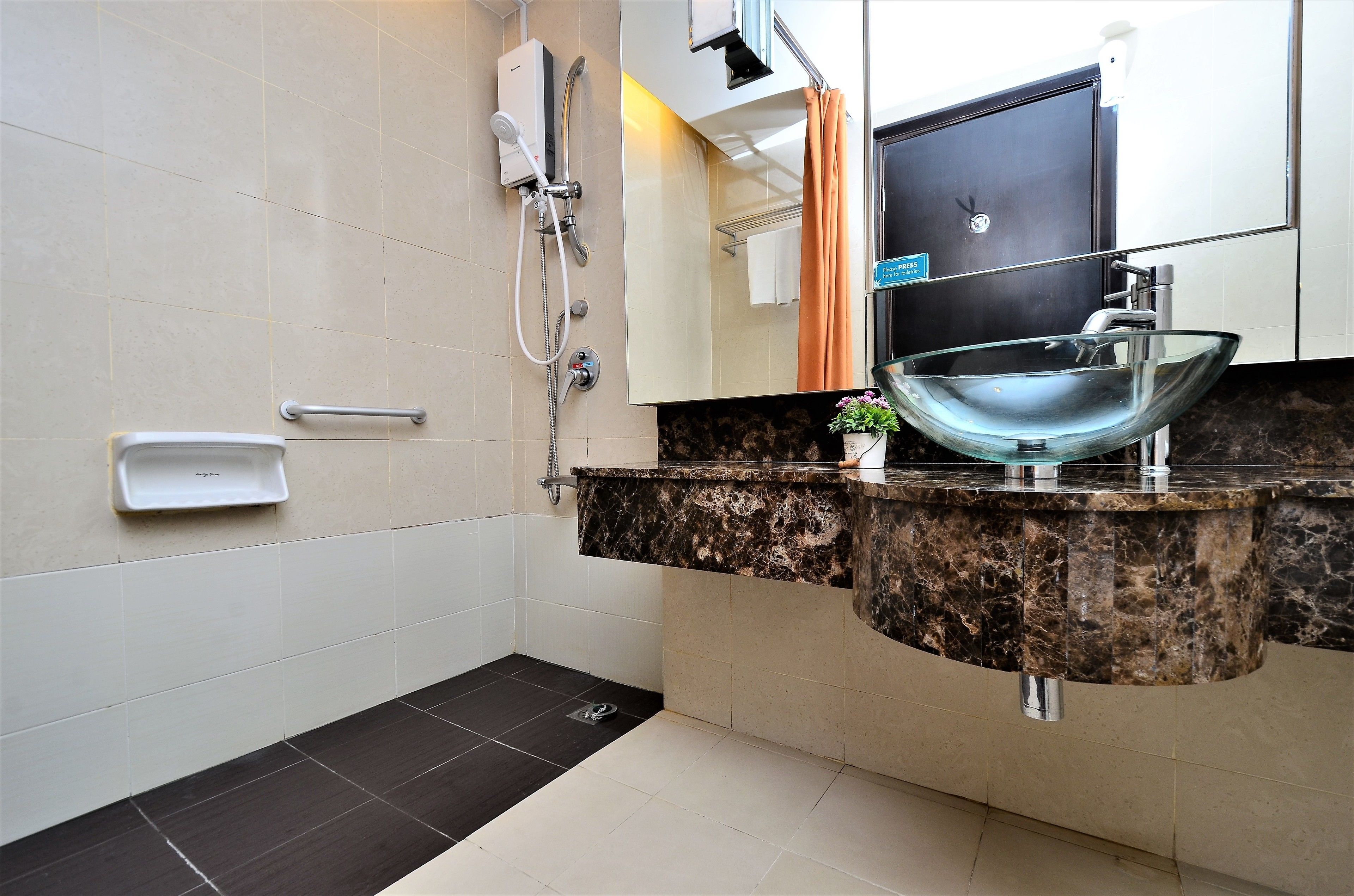 A modern bathroom with a glass bowl sink, a handheld showerhead, a towel rack, and a soap dish.