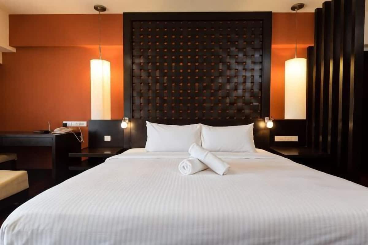 A hotel room with a large bed, two bedside tables, a desk, and a chair.