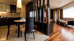 Uma sala de estar moderna com sofá, uma área de jantar com mesa e cadeiras, e uma cozinha com armários e micro-ondas.