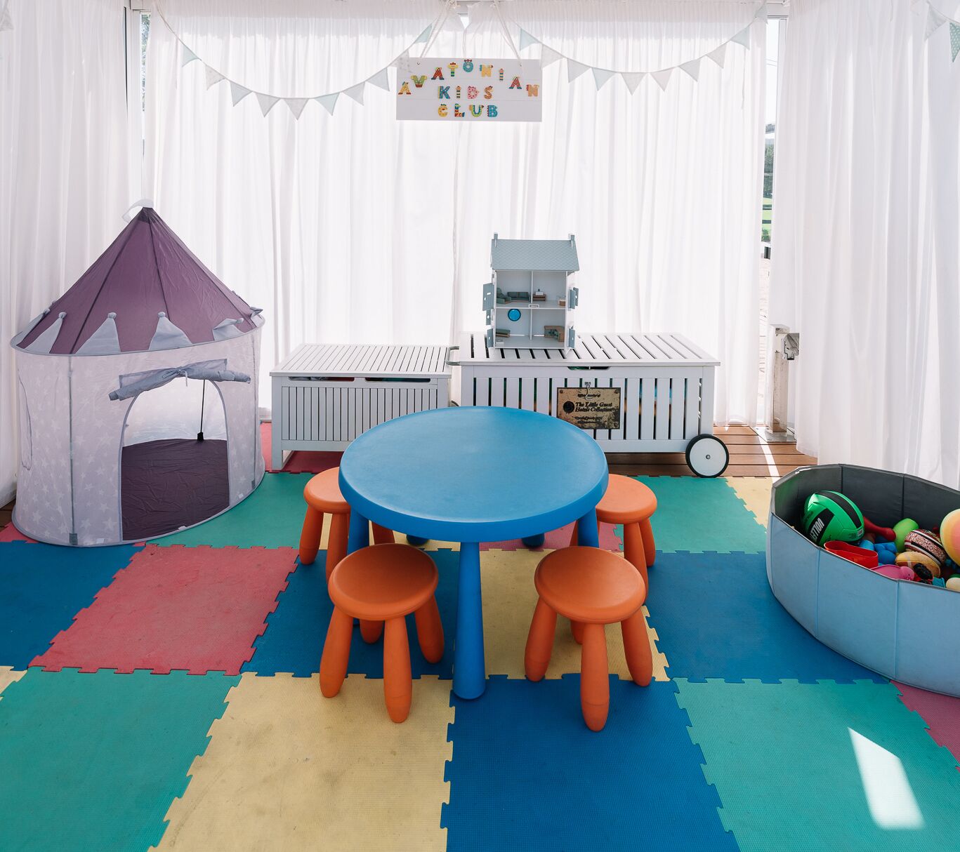 A children's play area with a tent, play table, and seating.