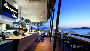 A modern bar area with a view of the sea at dusk. - Avaton Luxury Beach Resort - Relais & Chateaux (Aristotelis)