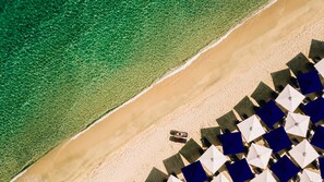 An aerial view of a beach with clear water, a sandy shore, and rows of umbrellas and chairs. - Avaton Luxury Beach Resort - Relais & Chateaux (Aristotelis)