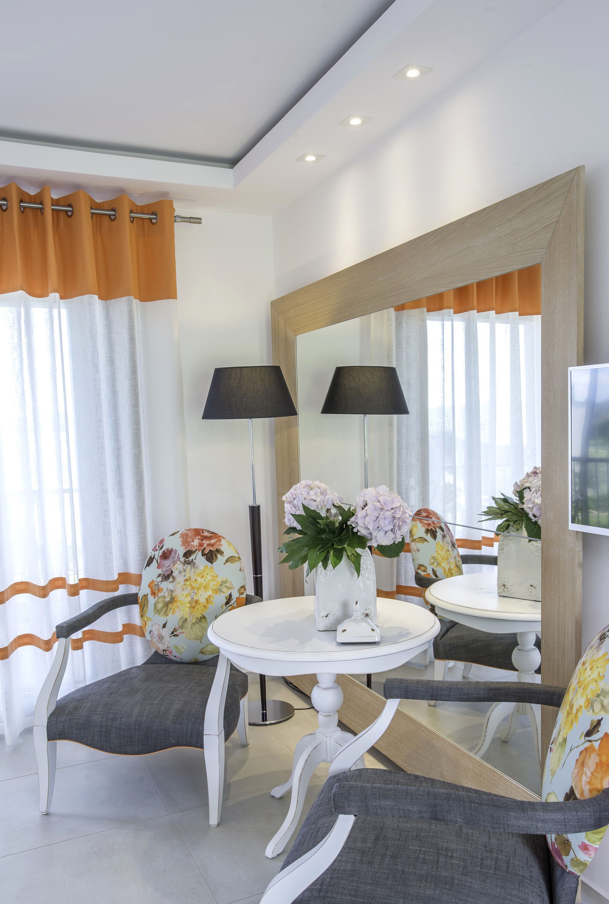 Una habitación moderna con una mesa redonda, dos sillas, un espejo y una lámpara.