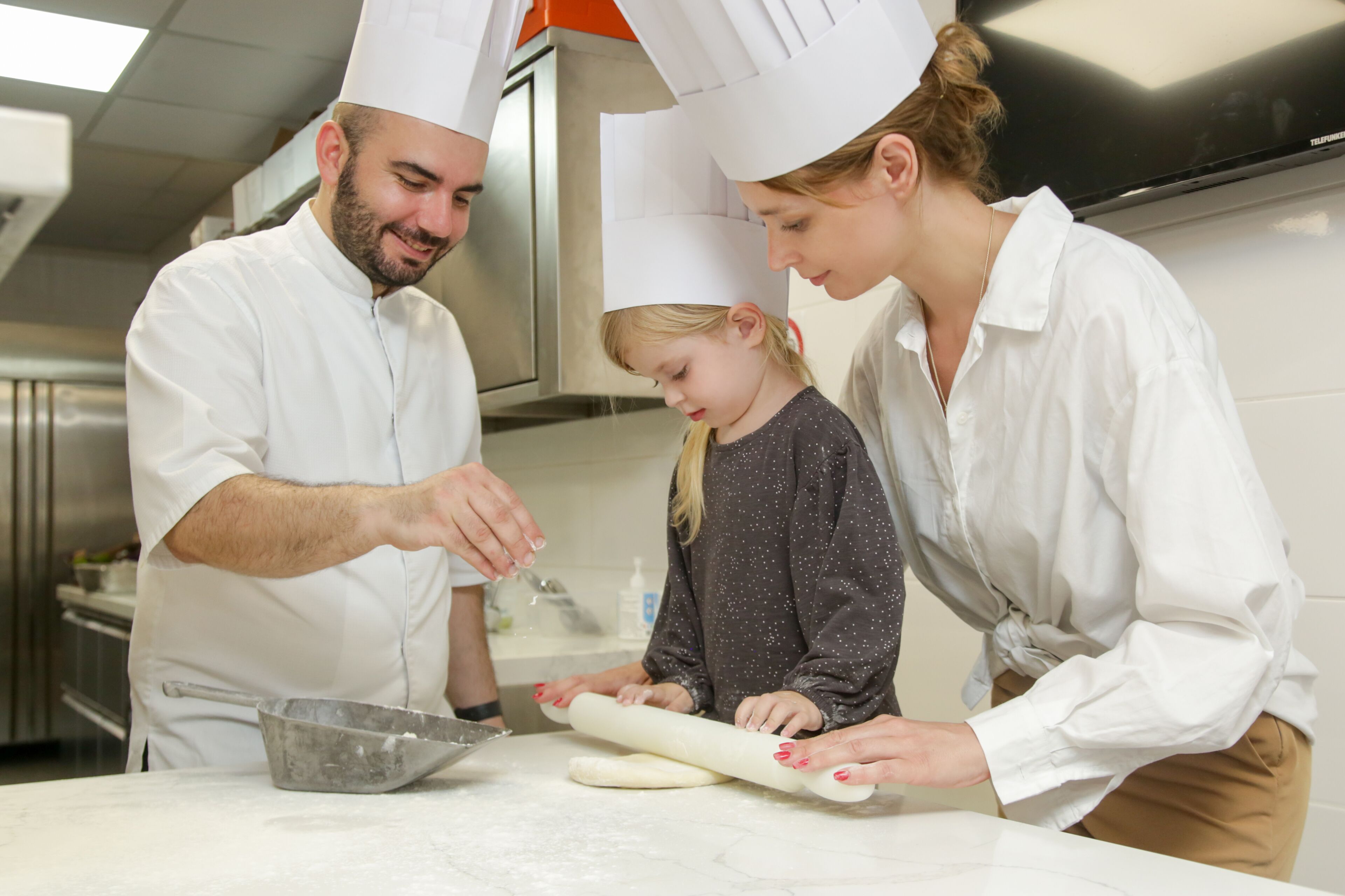 A kitchen with three people, one adult and two children, engaged in food preparation.