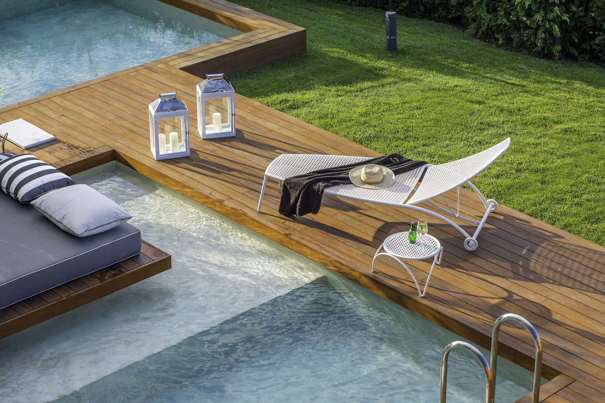 A wooden deck with a hot tub, lounge chairs, and a small table with candles.