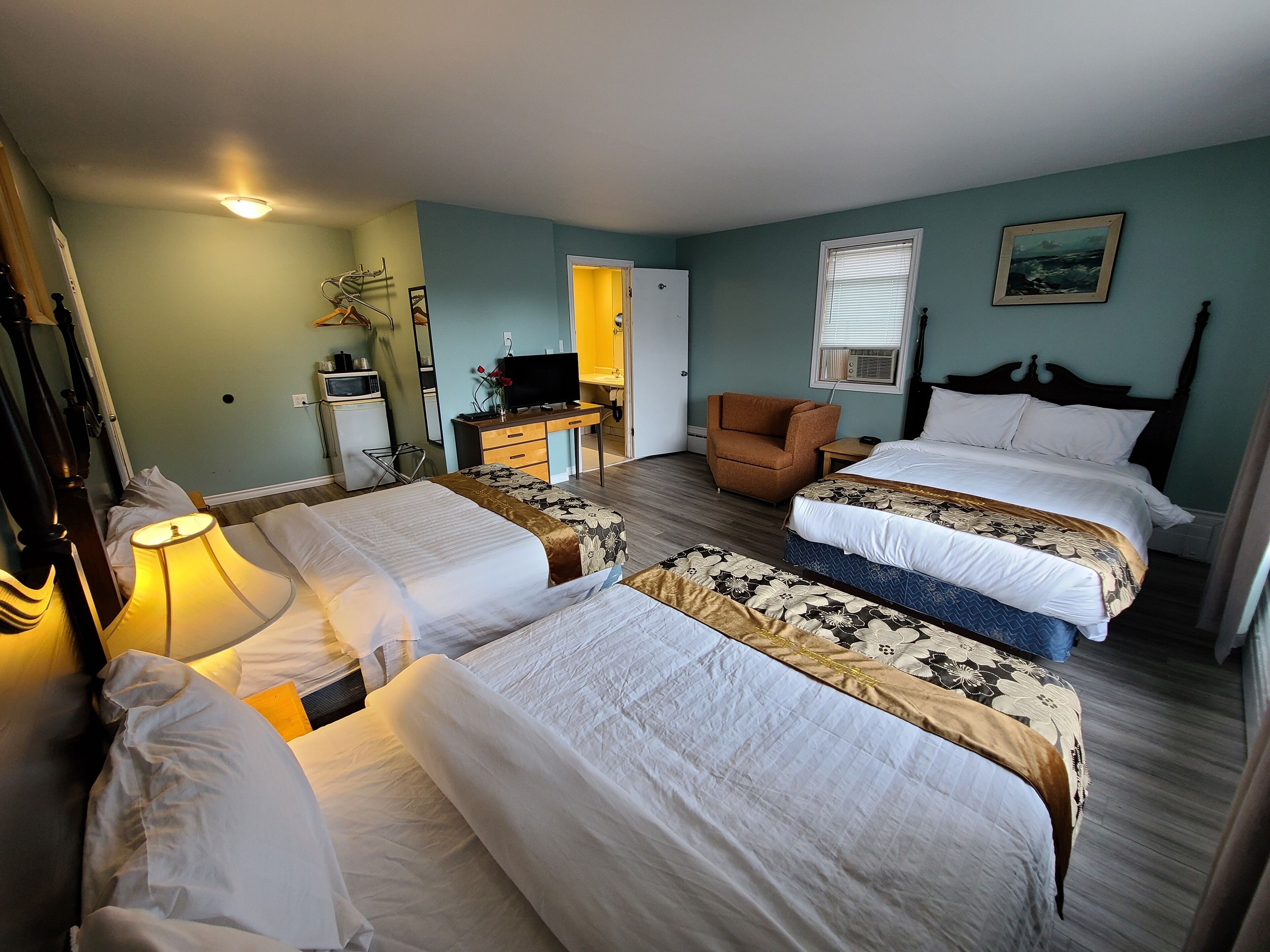 Une chambre d’hôtel avec deux lits, un bureau, une chaise et un téléviseur.