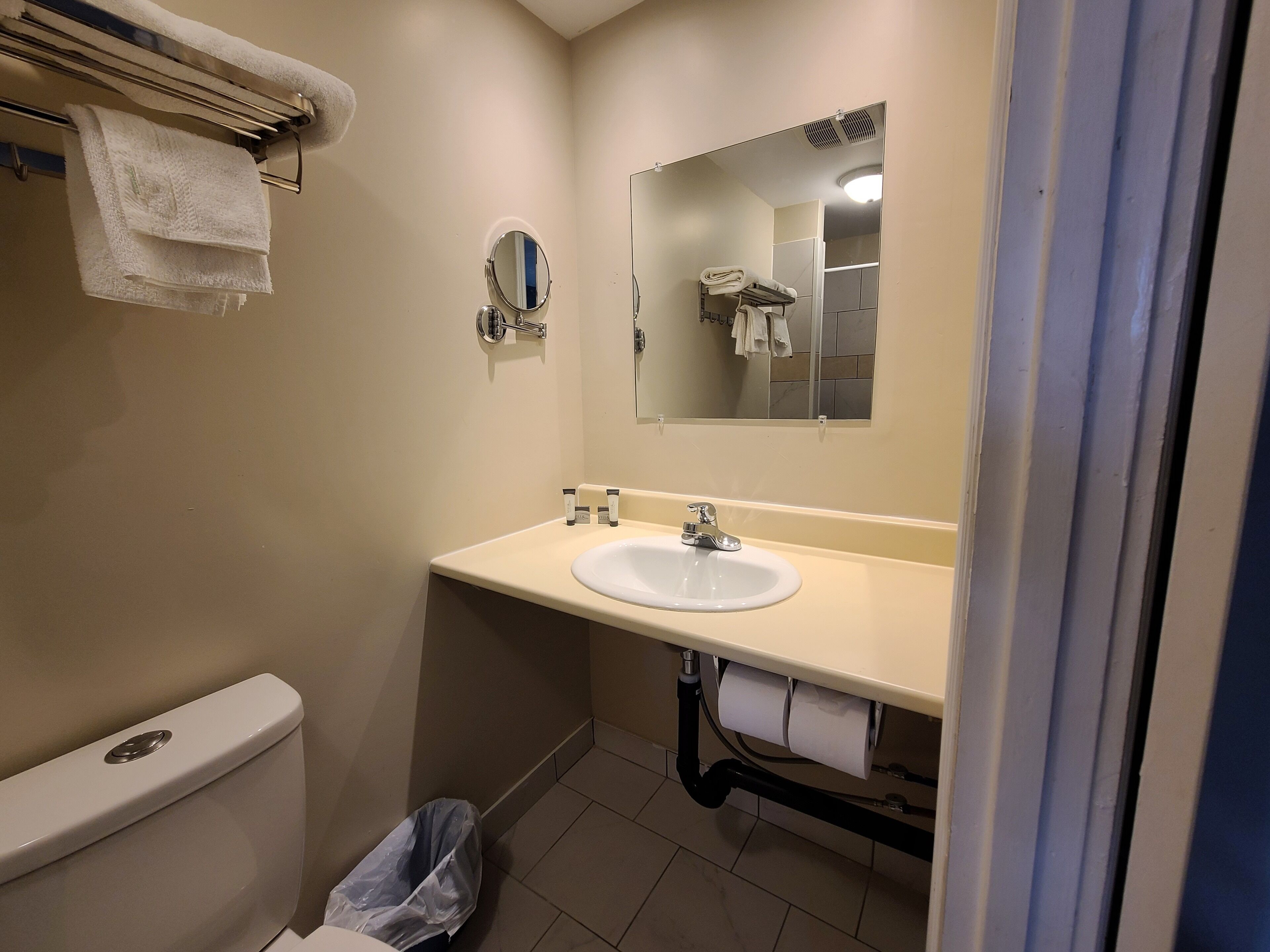 Un baño con inodoro, lavabo, espejo y toallero.