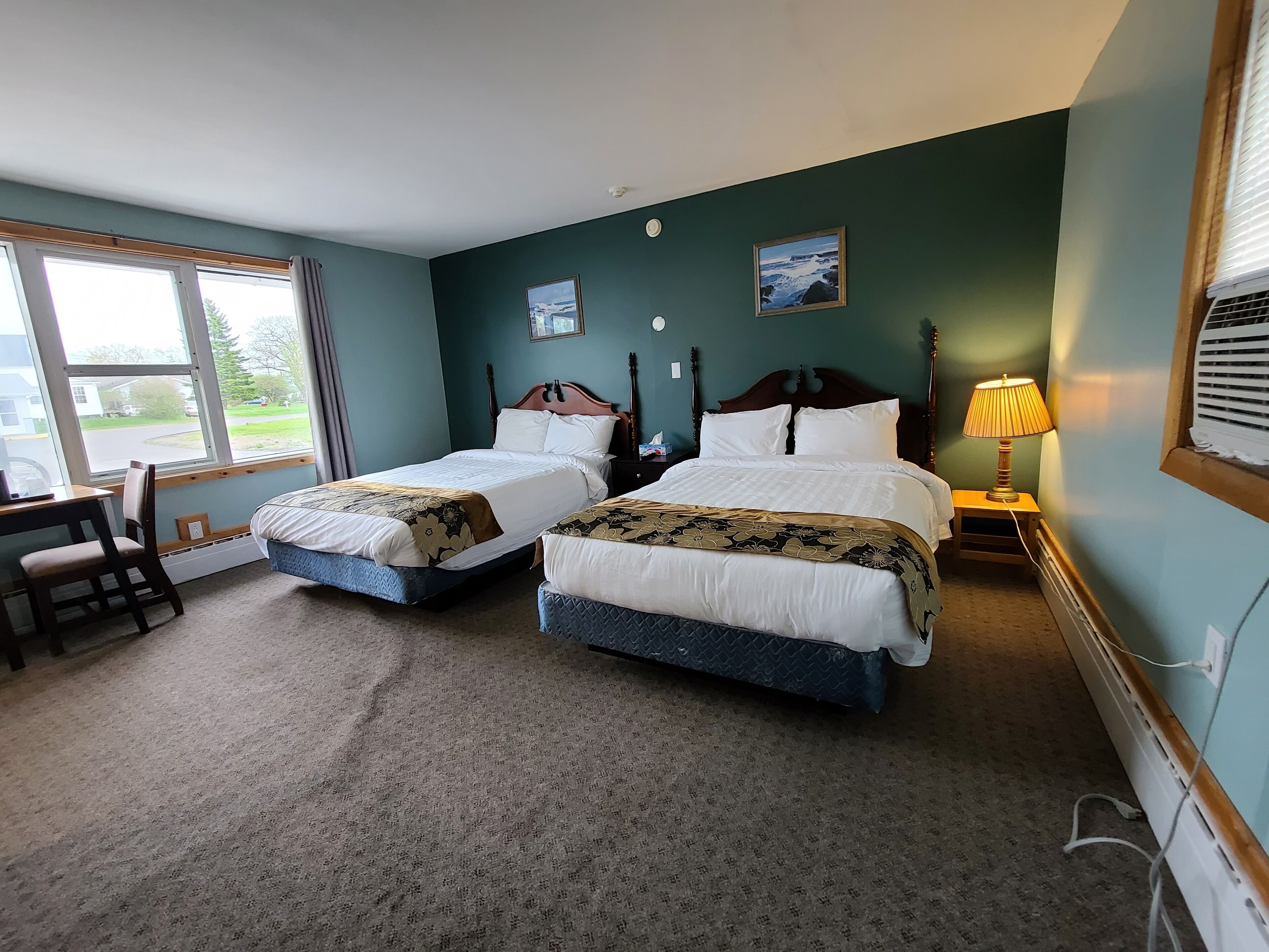 A hotel room with two beds, a desk, and a chair.