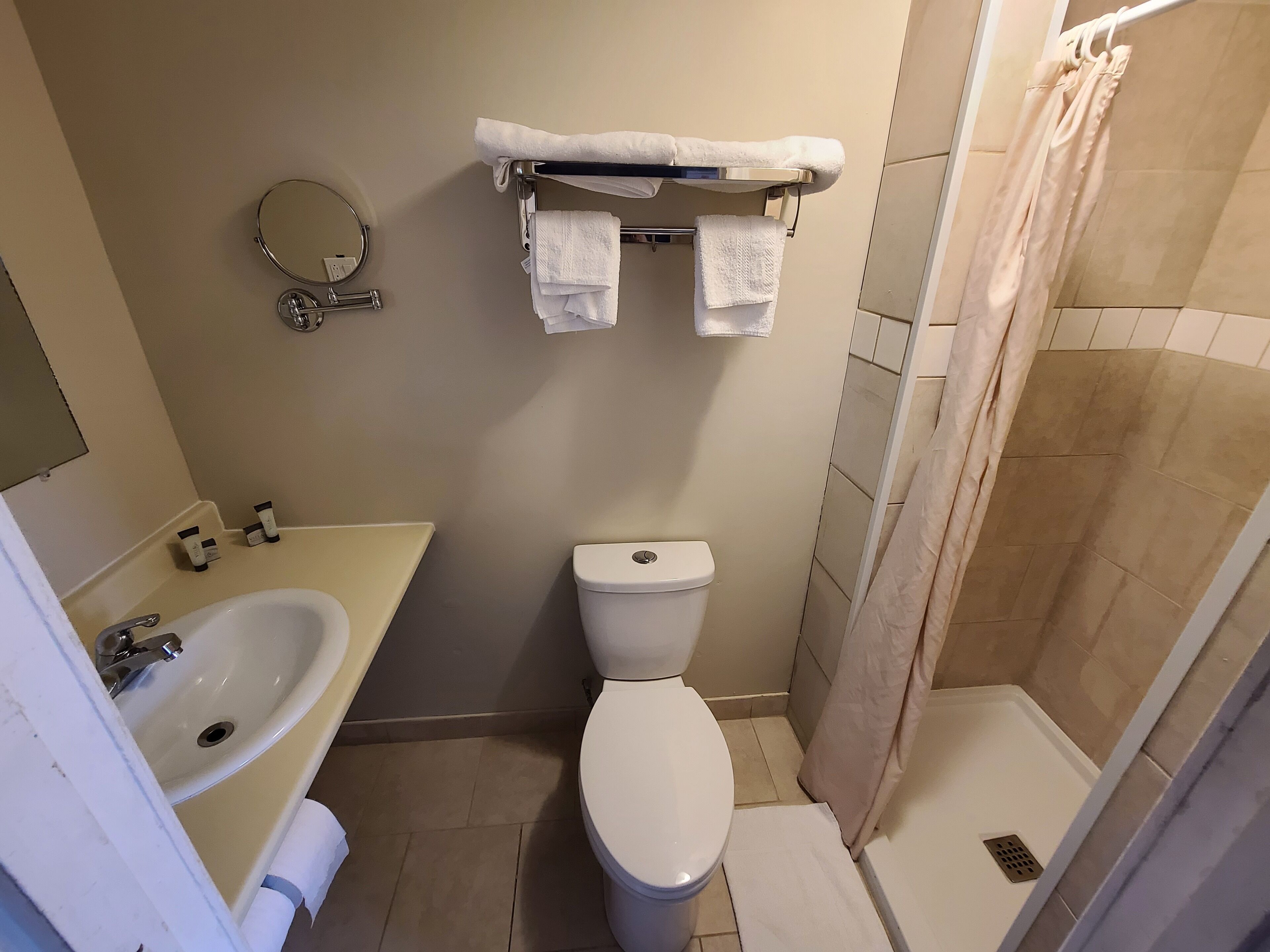 Un baño con lavamanos, inodoro y zona de ducha.