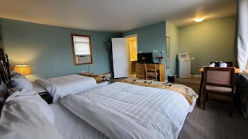 Une chambre d’hôtel avec deux lits, un bureau, une chaise, une télévision et une petite kitchenette.