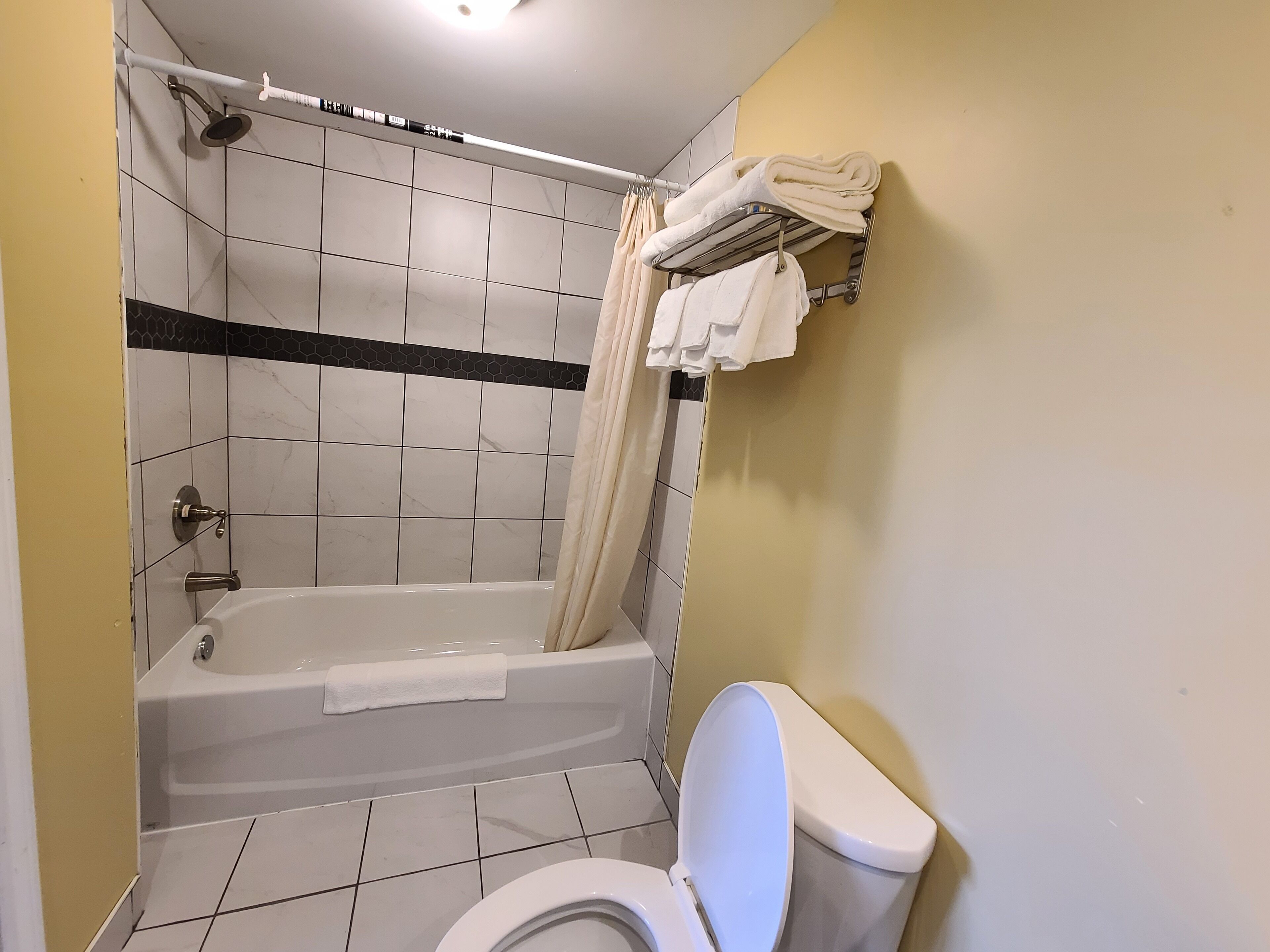 A bathroom with a bathtub, toilet, and a towel rack with towels.