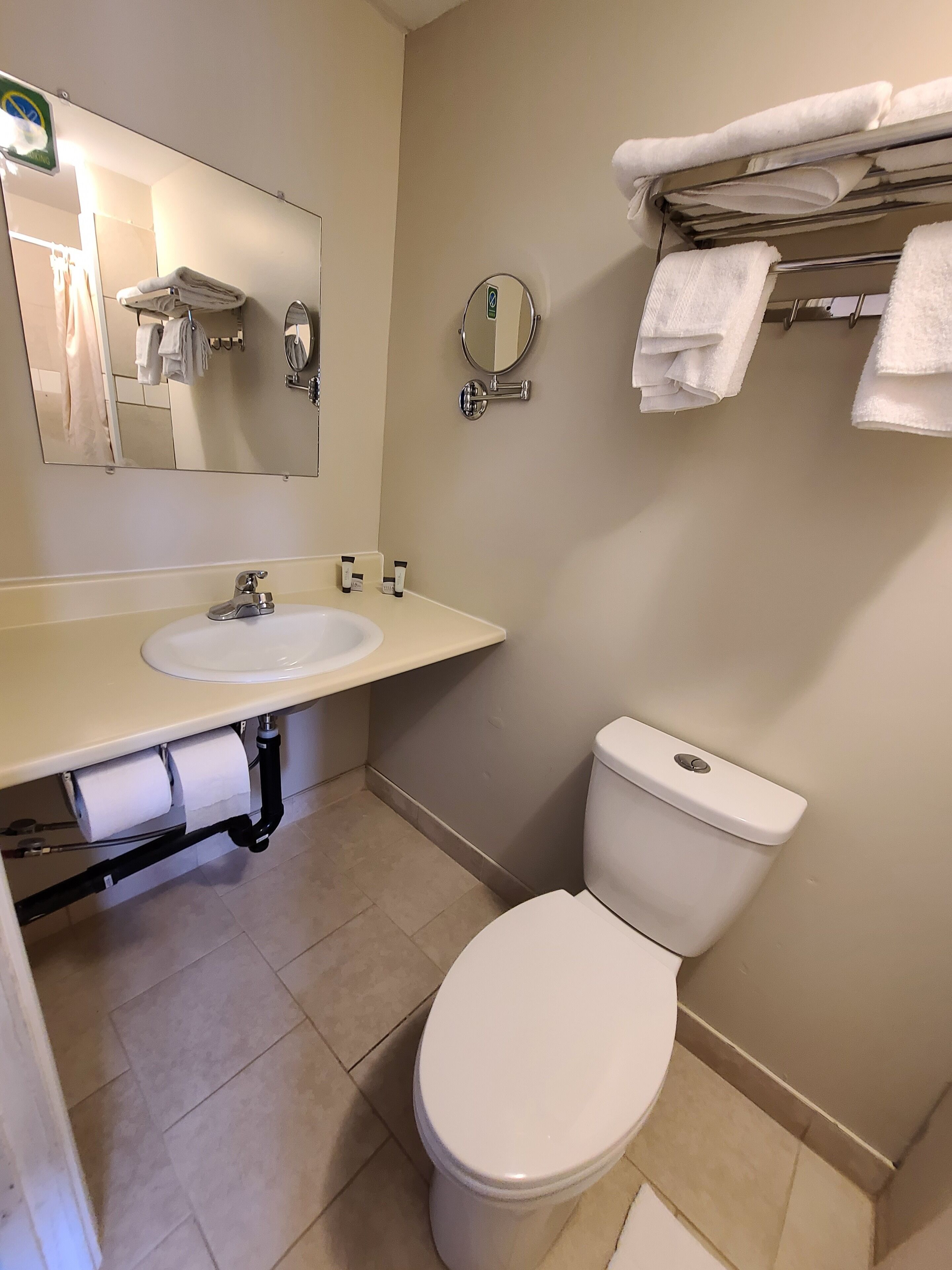 Une salle de bain équipée d’un lavabo, d’un miroir, de toilettes et d’un porte-serviettes.