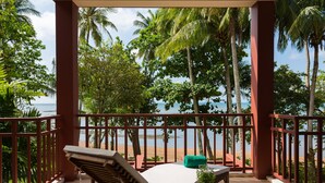 A balcony with a view of the beach, palm trees, and a lounge chair. - Amatapura Beach Villa 15 (Krabi)