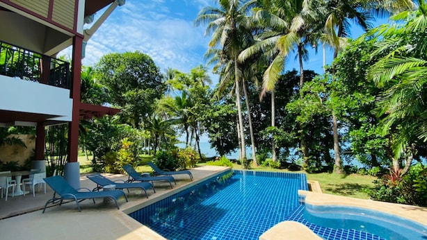 A pool area with lounge chairs and a hot tub, surrounded by palm trees and a clear sky. - Amatapura Beach Villa 15 (Krabi)