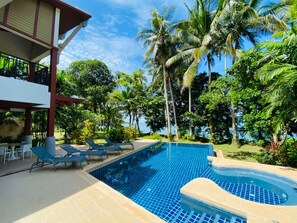 A pool area with lounge chairs and a hot tub, surrounded by palm trees and a clear sky. - Amatapura Beach Villa 15 (Krabi)