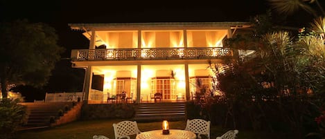 A two-story building with a balcony, outdoor seating area, and steps leading up to the entrance.
