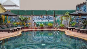 A swimming pool with tiled flooring, lounge chairs, potted plants, and a mural on the wall. - Side Walk Never Die (Siem Reap)