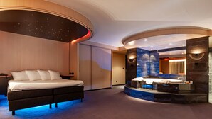 Une chambre moderne dotée d’un grand lit, d’une baignoire intégrée et d’un plafond au design incurvé.