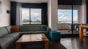 Un salon moderne avec un canapé gris, une table basse en bois et une vue sur un balcon agrémenté d’une table et de chaises.
