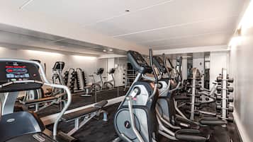 Une salle de sport moderne dotée de divers équipements pour le cardio et le renforcement musculaire, notamment des tapis de course, des appareils elliptiques et des poids libres.