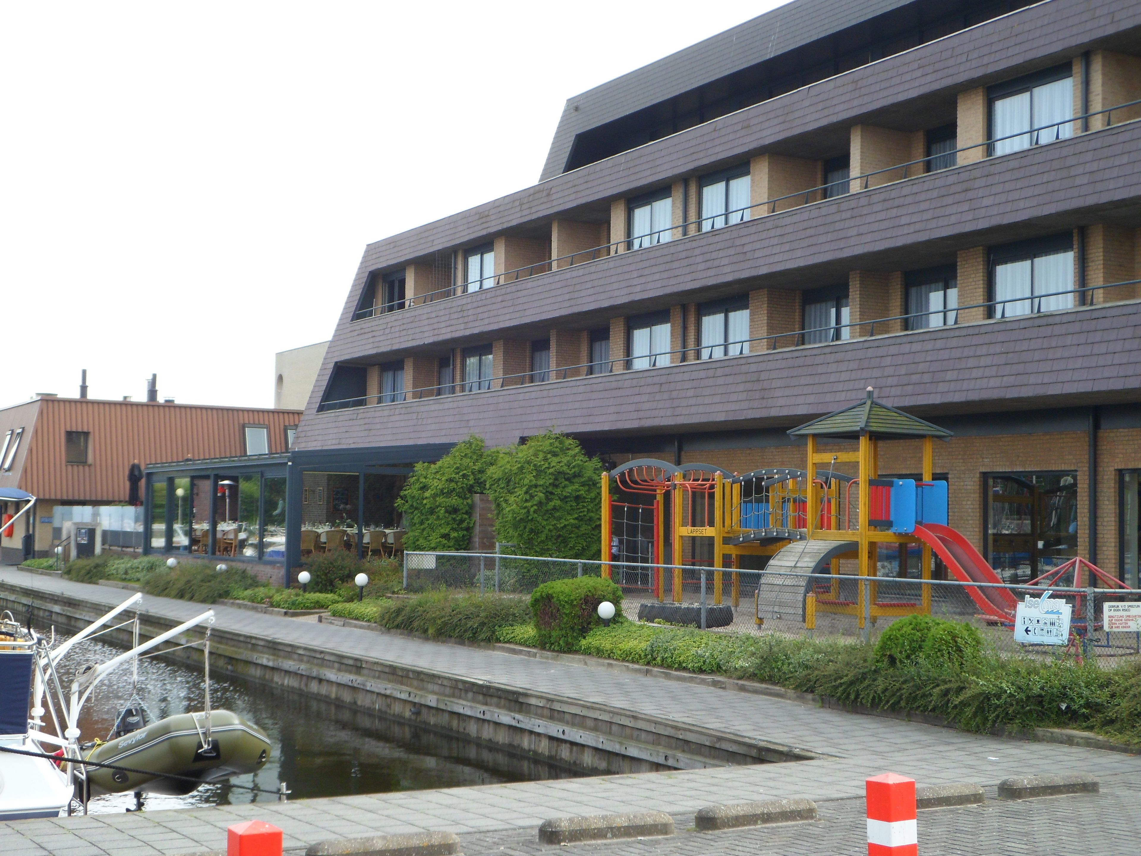 Un edificio con un parque infantil, un canal y un bote amarrado junto al agua.