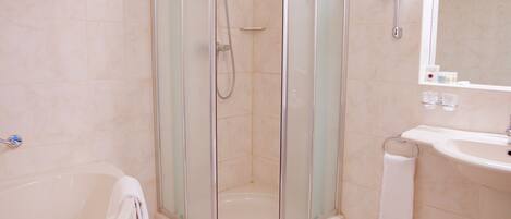 A modern bathroom with a glass-enclosed shower, a white bathtub, and a sink with a mirror.