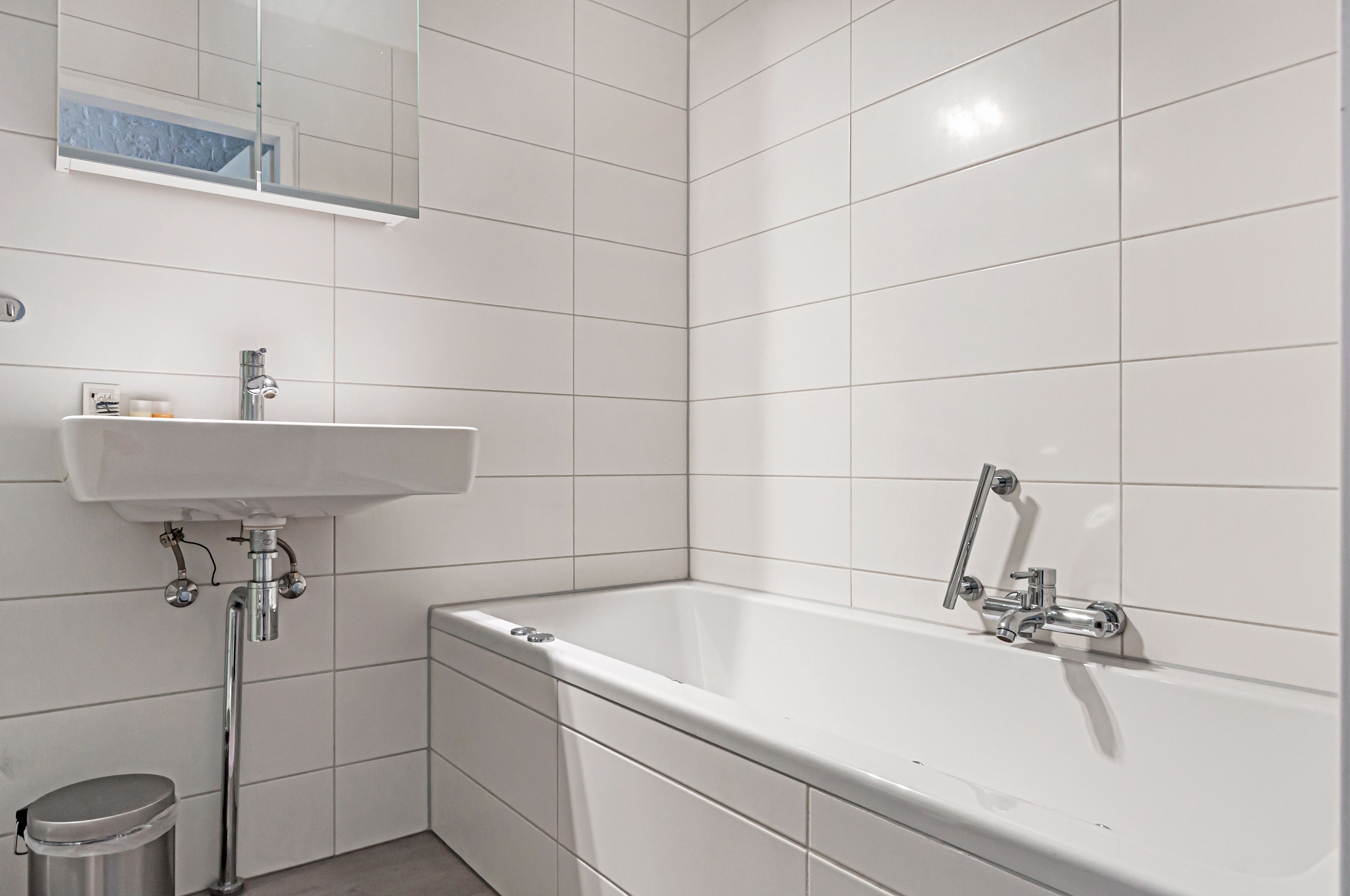 Et moderne badeværelse med en hvid vask, badekar og toilet.