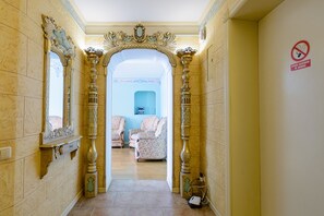 A hallway with ornate gold pillars, a blue wall in the background, and two upholstered chairs. - Kiev Accommodation Hotel Service (Kyiv)