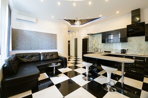 A modern kitchen with a black and white checkered floor, a black sofa, and a bar area. - Kiev Accommodation Hotel Service (Kyiv)