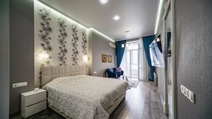 Un dormitorio moderno con una cama grande, una mesita de noche, una silla y una ventana con cortinas.