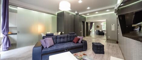 Una sala moderna con un sofá gris, una mesa de centro blanca y un otoman negro.