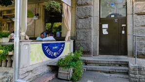 Un edificio con fachada de piedra, puerta de entrada metálica y un letrero que dice "ARBEQUINA".