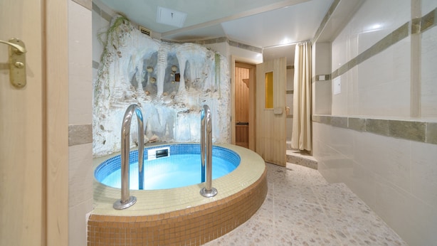 Un jacuzzi con interior de baldosas, una puerta de madera y suelo de baldosas.