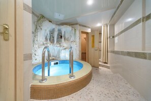 Un bain à remous avec un revêtement intérieur en carrelage, une porte en bois et un sol carrelé.