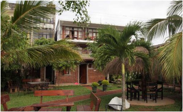 A courtyard with palm trees, a brick building, and outdoor seating.