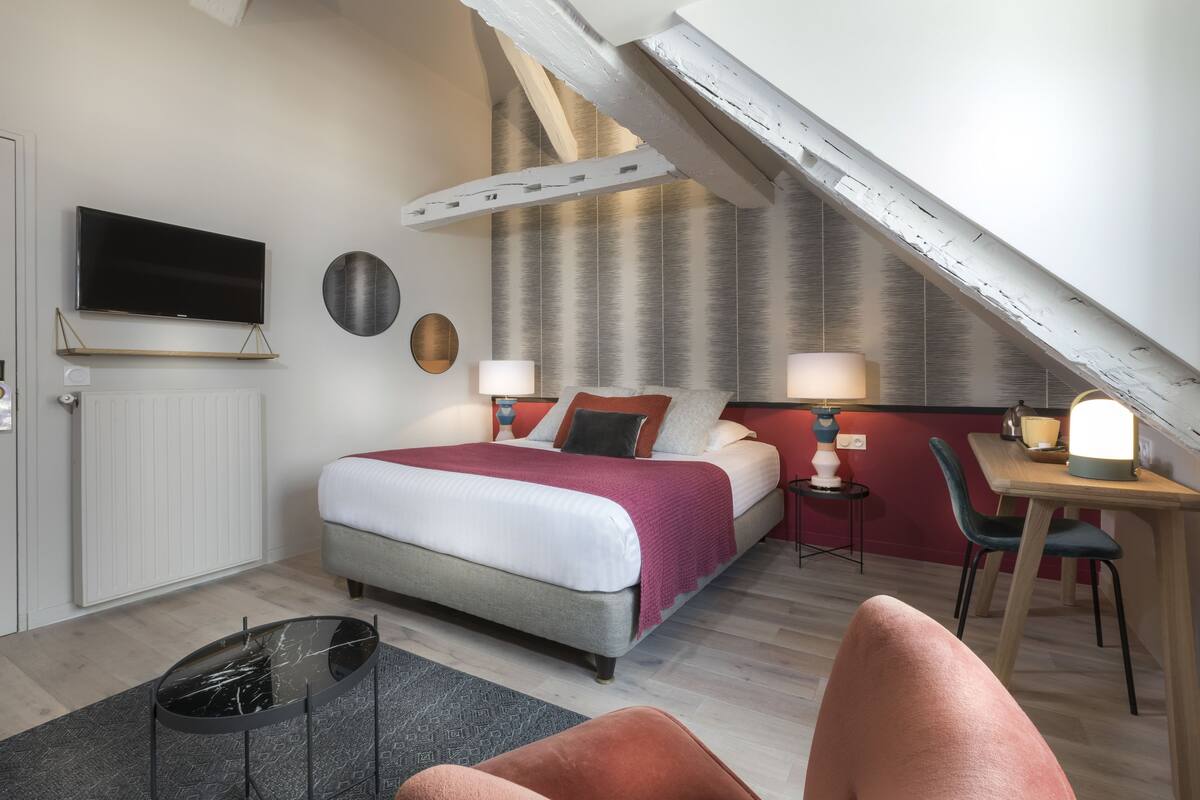 Moderni hotellihuone, jossa on suuri sänky, työpöytä ja televisio.