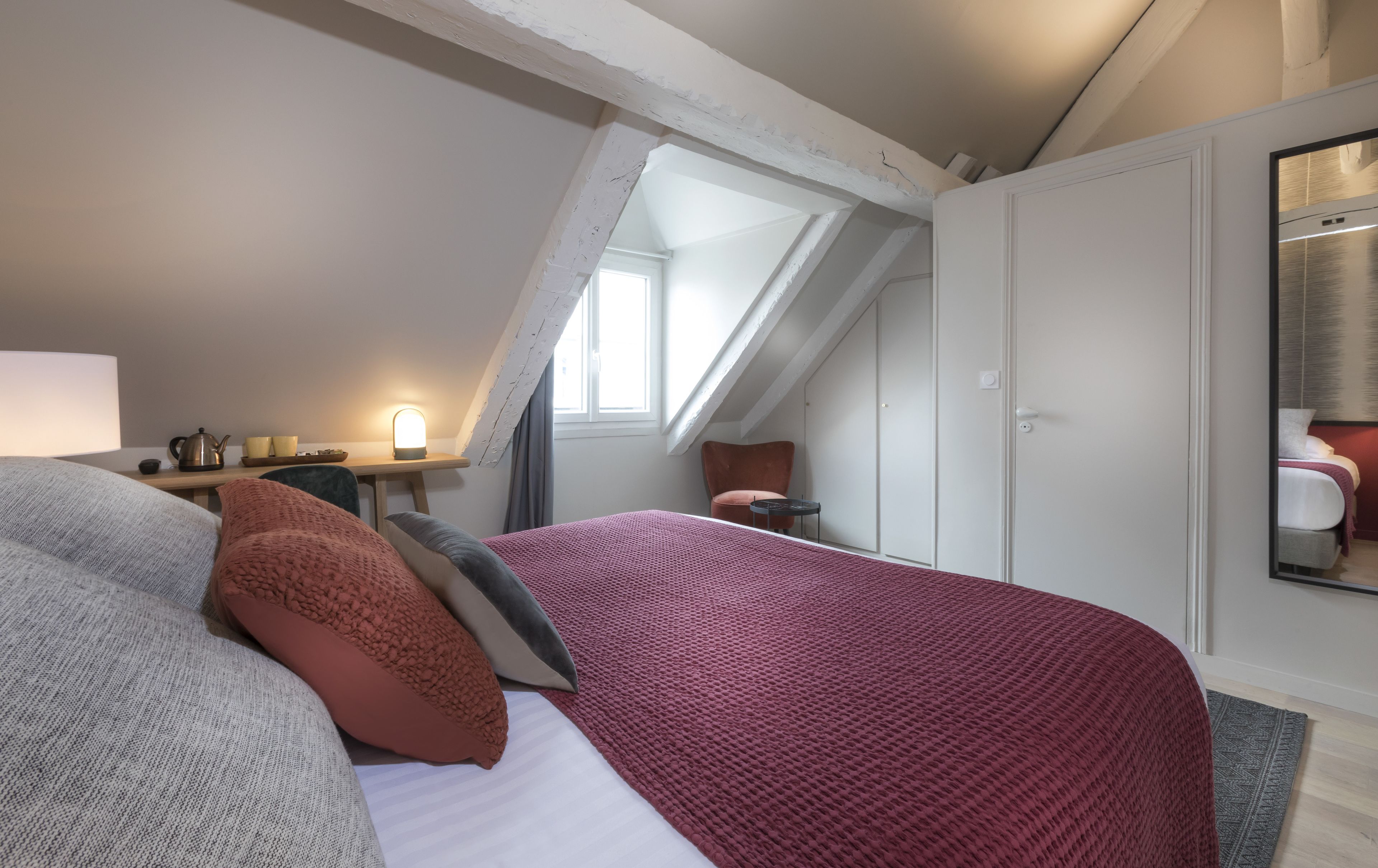 A bedroom with a large bed, a desk, a chair, and a window.