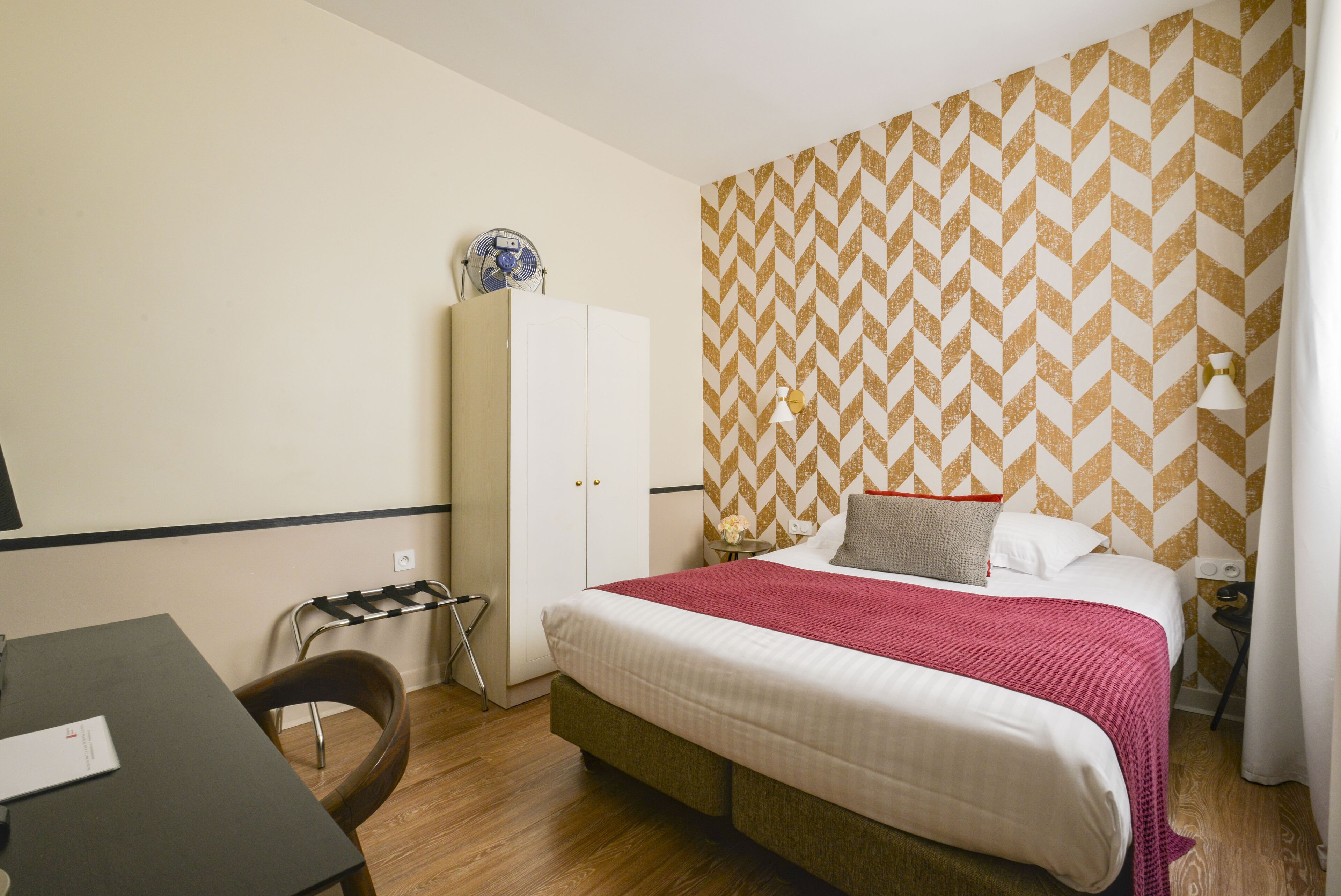 A bedroom with a bed, a wardrobe, a desk, and a chair.