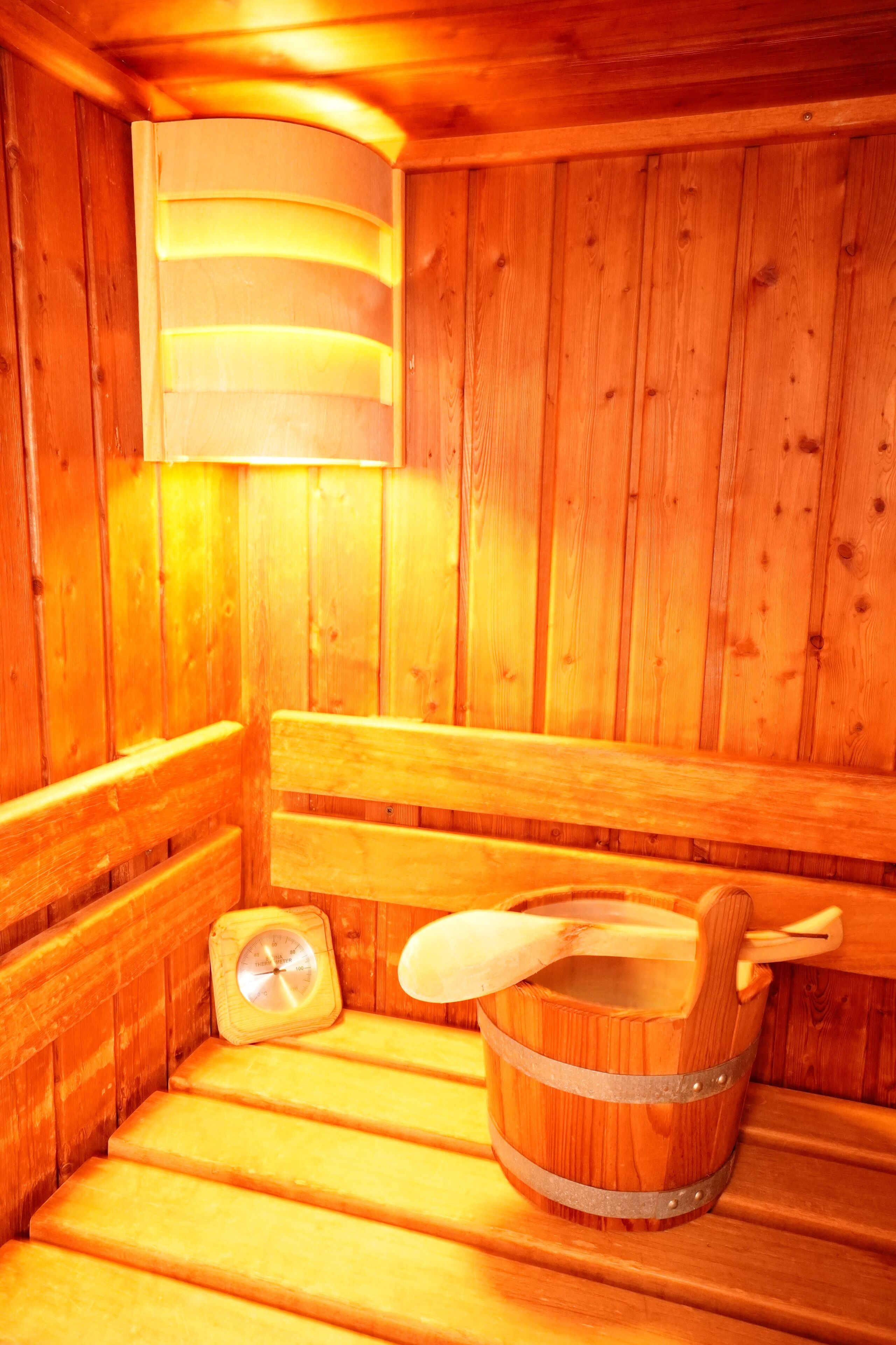 A wooden sauna with benches and a wooden bucket.