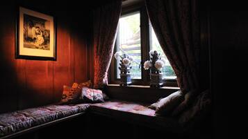 A dimly lit room with a bench, a framed picture on the wall, and a window with curtains.